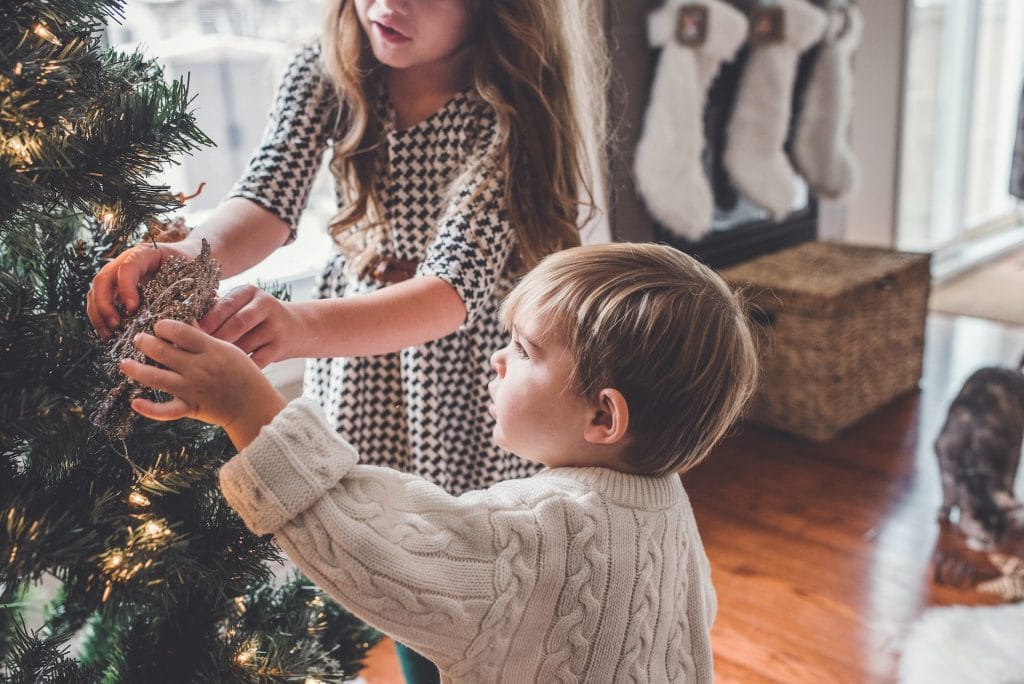 Boy and girl decorating the Christmas tree inside the room paige cody bdse1gz3EPg unsplash
